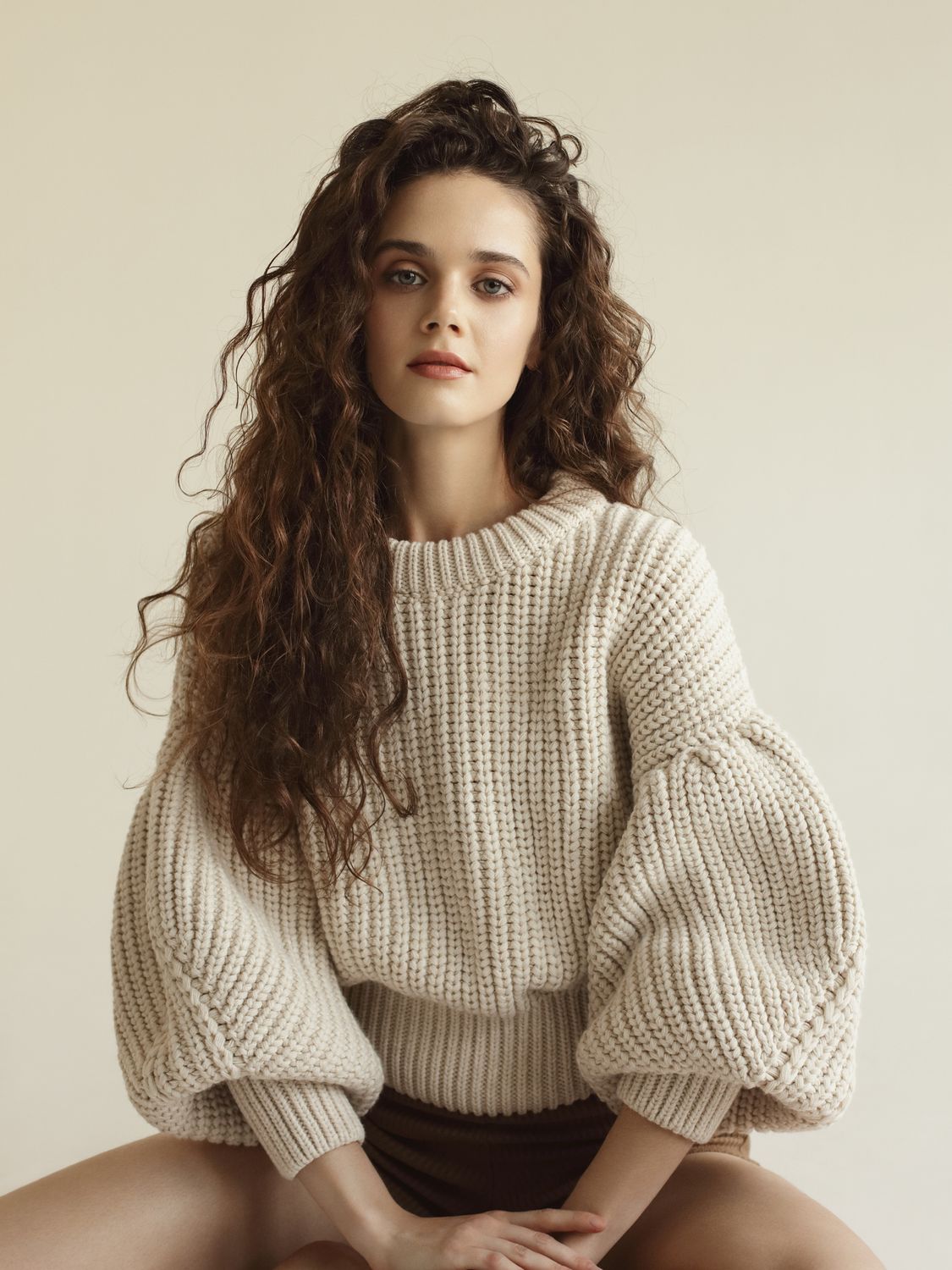 Model in oversized knitted sweater, neutral background.