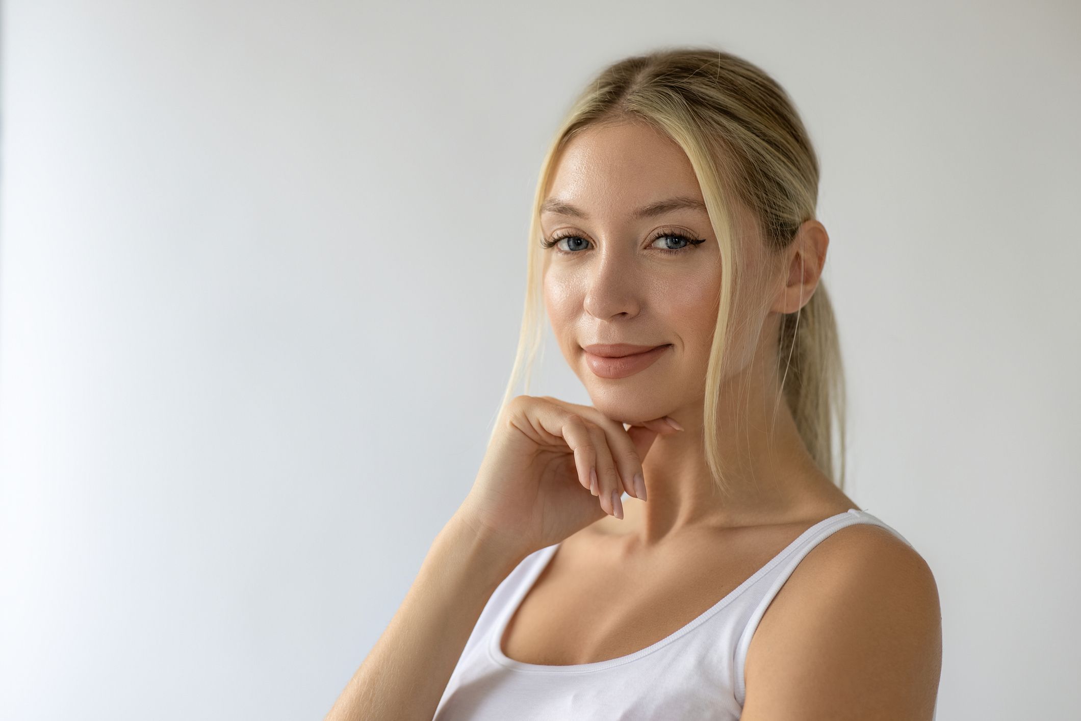 Smiling woman with long blonde hair, thoughtful pose.
